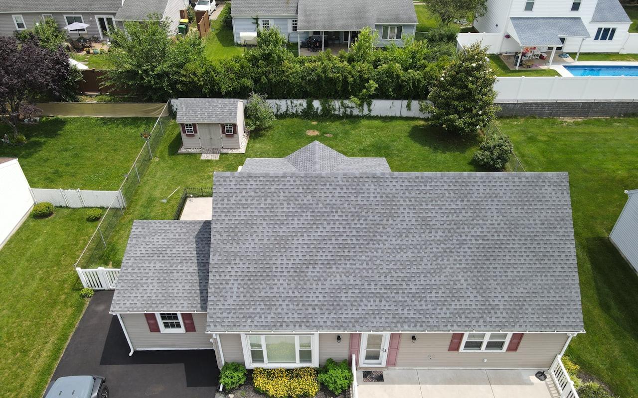 Aerial view of a suburban home with a new grey asphalt shingle roof