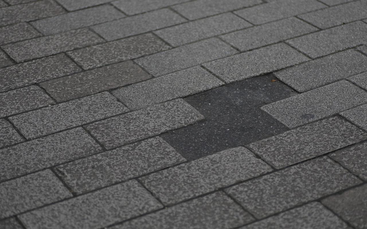Asphalt shingle roof with a missing shingle exposing the layer beneath