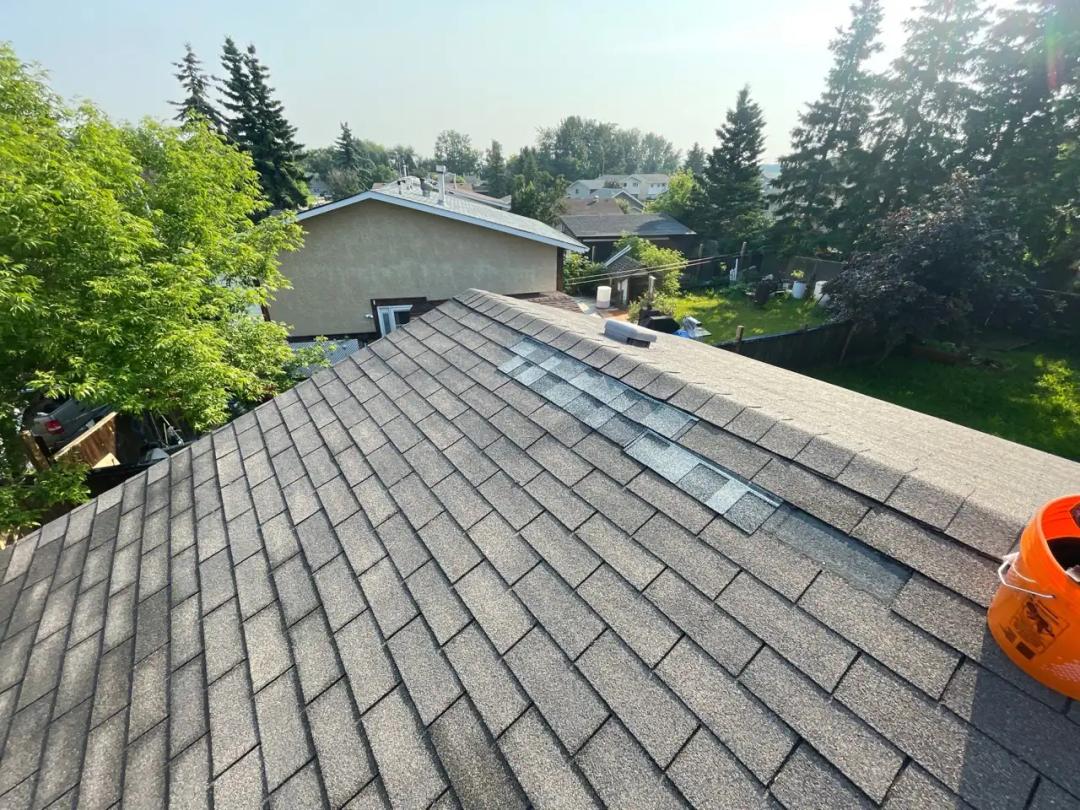 Roof ridge with a section of wind-damaged shingles in Stony Plain
