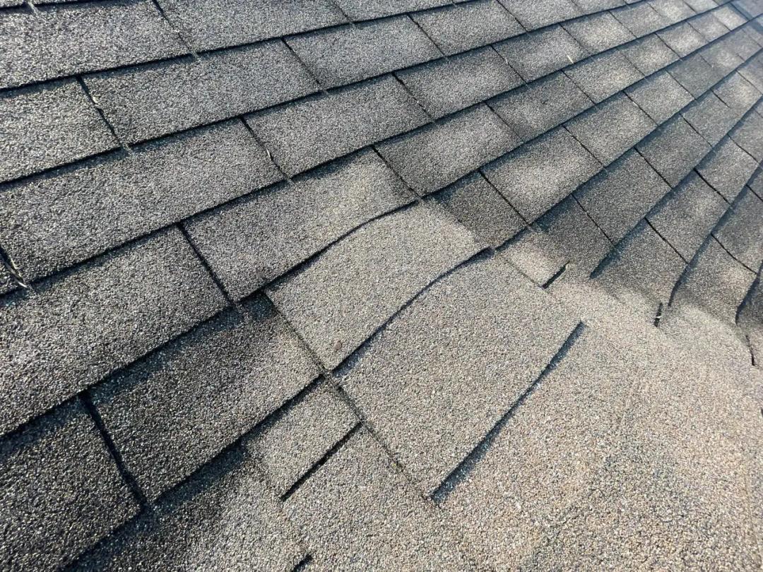 Lifted and torn shingles from wind damage