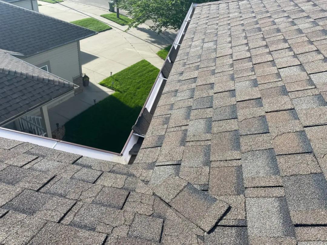 Wind-lifted shingles exposing the roof beneath